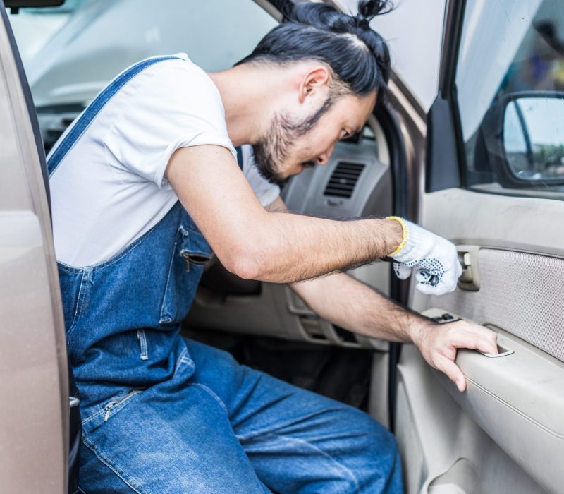 Fixing car engine in automobile repair garage. Handsome mechanic